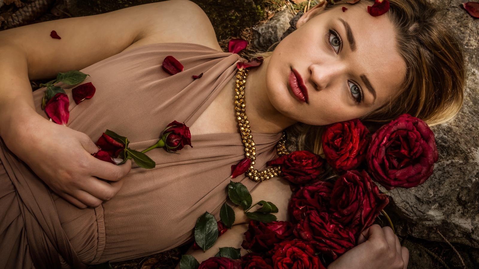 Красивая девушка в платье лежит на земле с розами