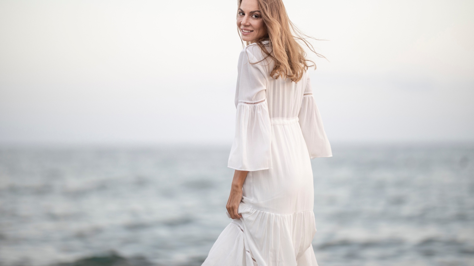 Красивая девушка в белом платье у моря