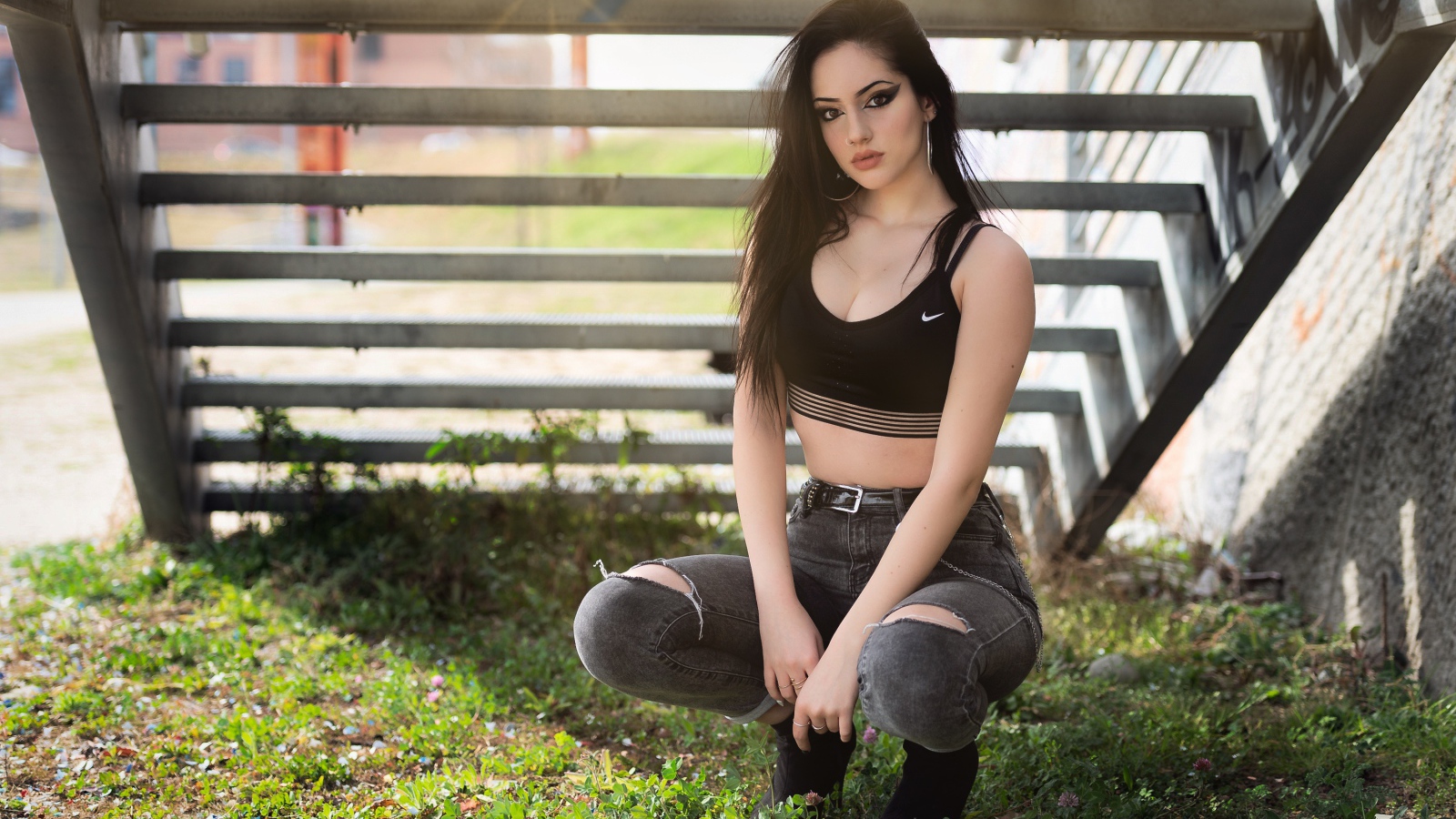 Красивая девушка сидит под лестницей 