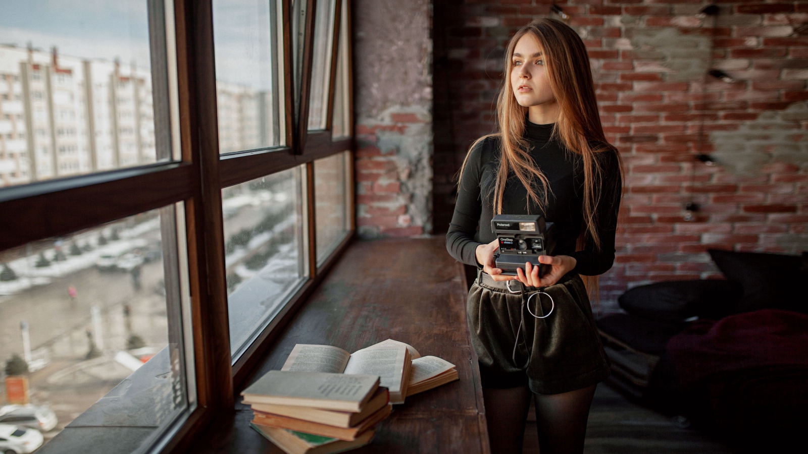 Красивая девушка с фотоаппаратом в руках у окна 