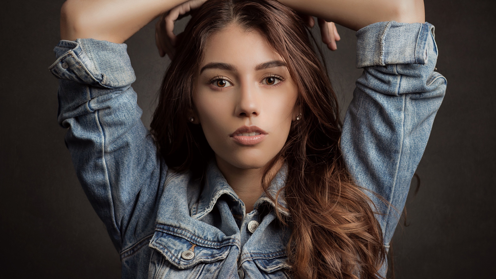 Красивая длинноволосая шатенка в джинсовой куртке 