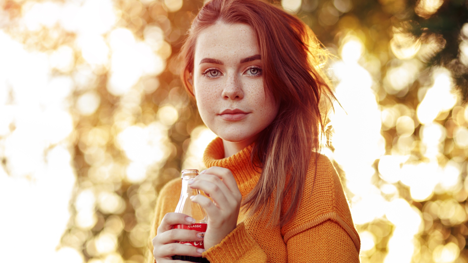 Красивая рыжеволосая девушка с бутылкой кока колы в руке 