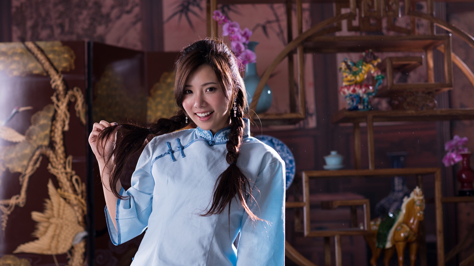 Красивая улыбающаяся девушка азиатка с косами на голове