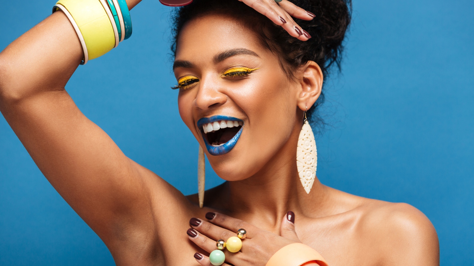 Красивая молодая девушка с ярким разноцветным макияжем на голубом фоне