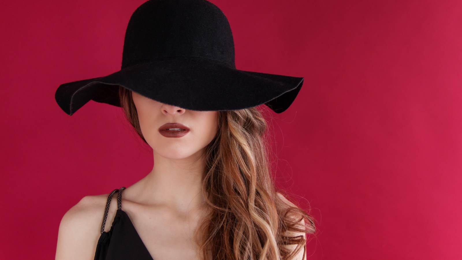 Большая черная шляпа закрывает лицо девушки