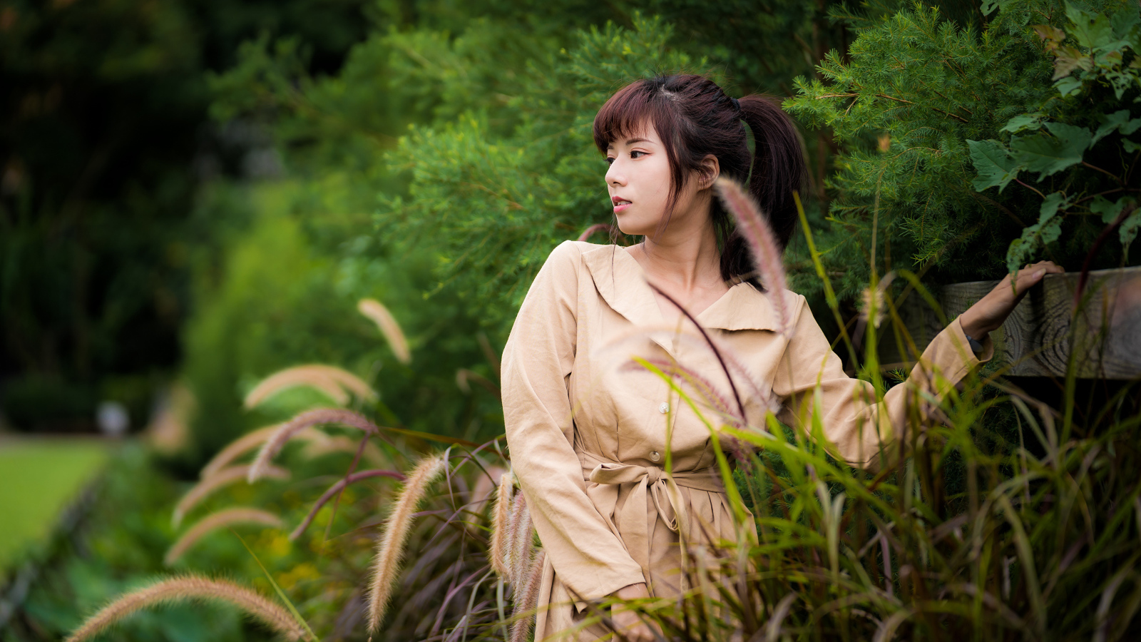 Милая азиатка в пальто в парке 