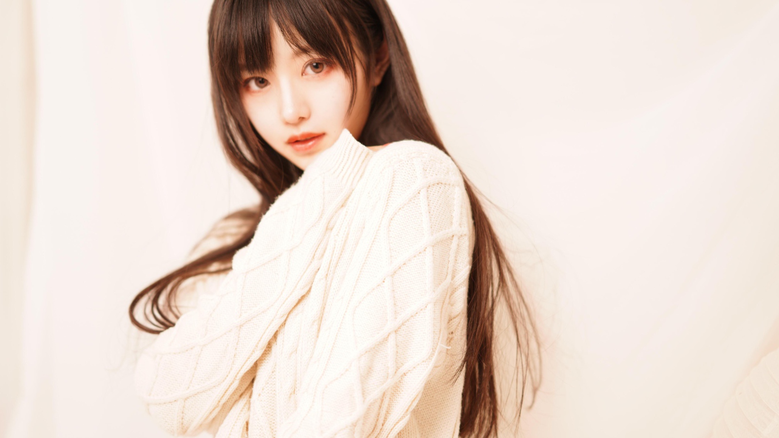 Милая азиатка в белом свитере на розовом фоне