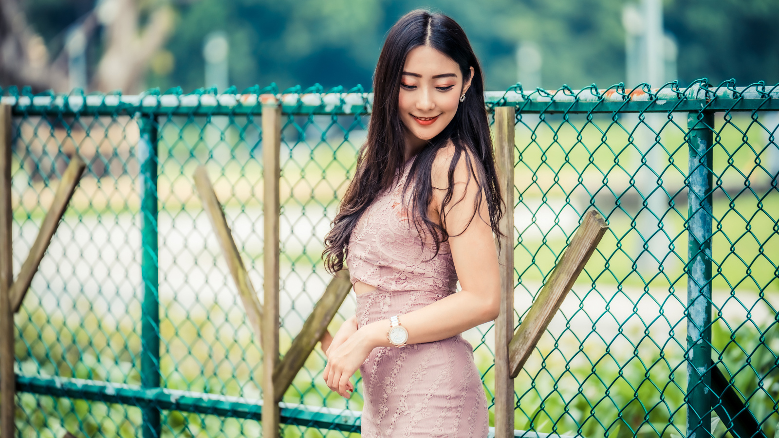 Милая азиатка в платье стоит под забором