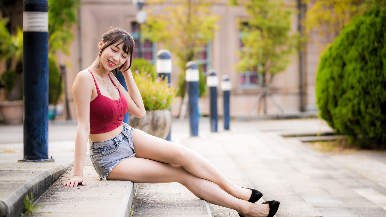 Милая улыбающаяся девушка азиатка сидит на ступенях