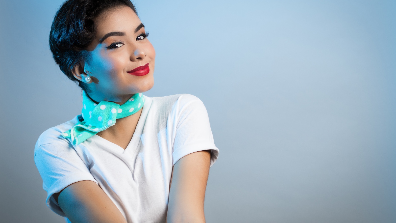 Милая улыбающаяся девушка с шарфом на шее на сером фоне