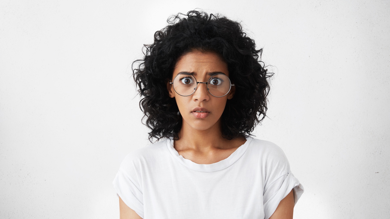 Темноволосая девушка в белой футболке на сером фоне