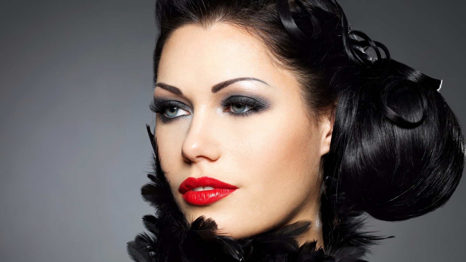 Лицо брюнетки с красивой прической на голове на сером фоне