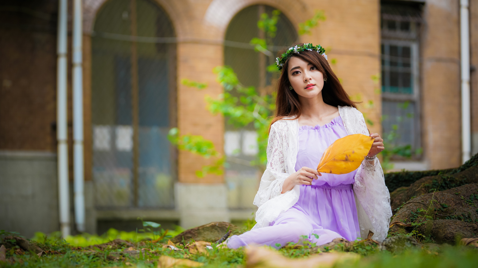 Девушка в красивом платье сидит на траве 