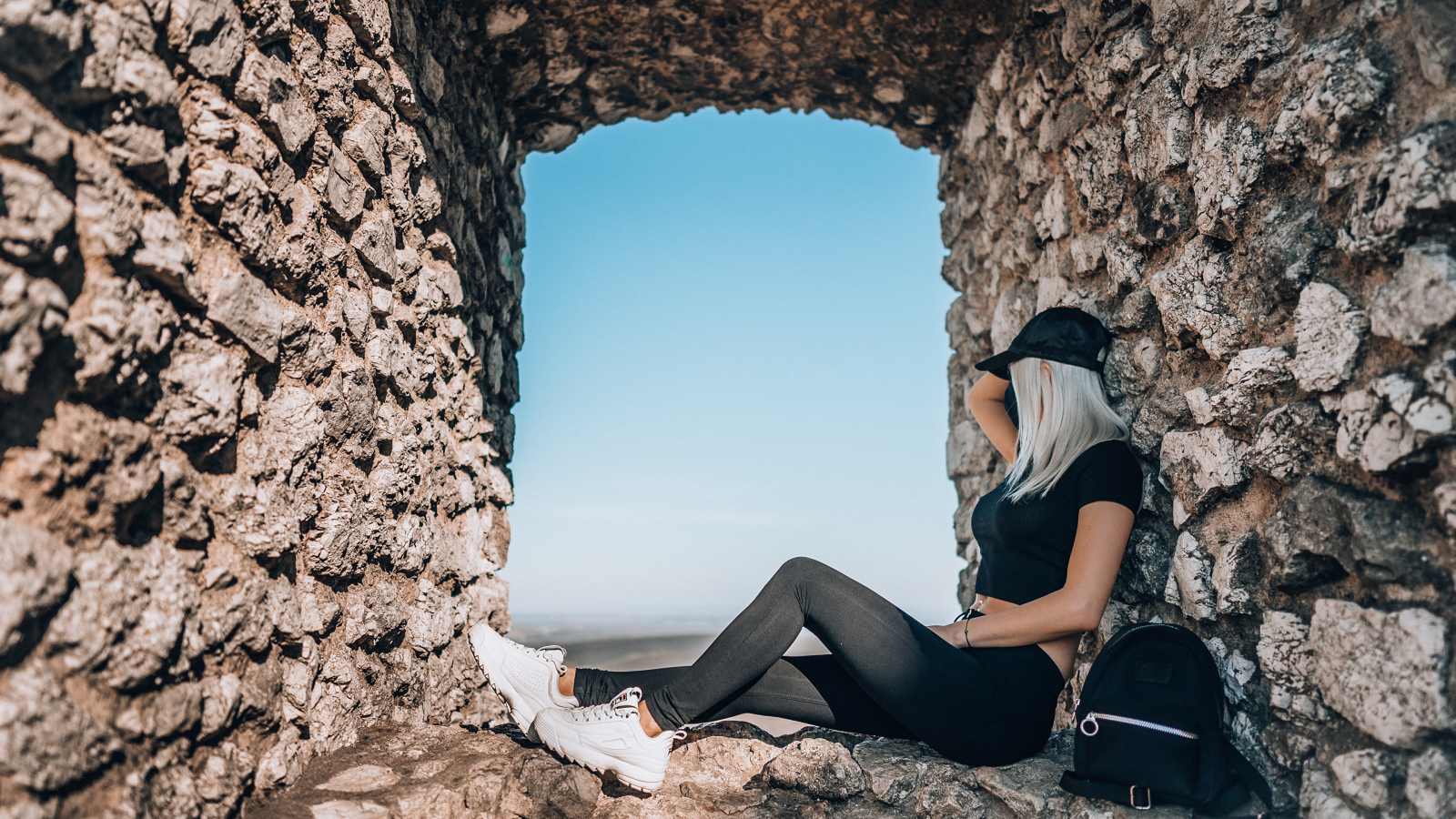 Девушка сидит в окне старого здания 