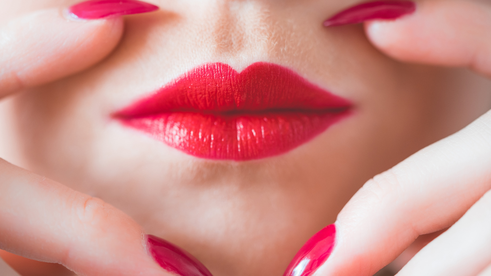 Руки с длинными красными ногтями у губ