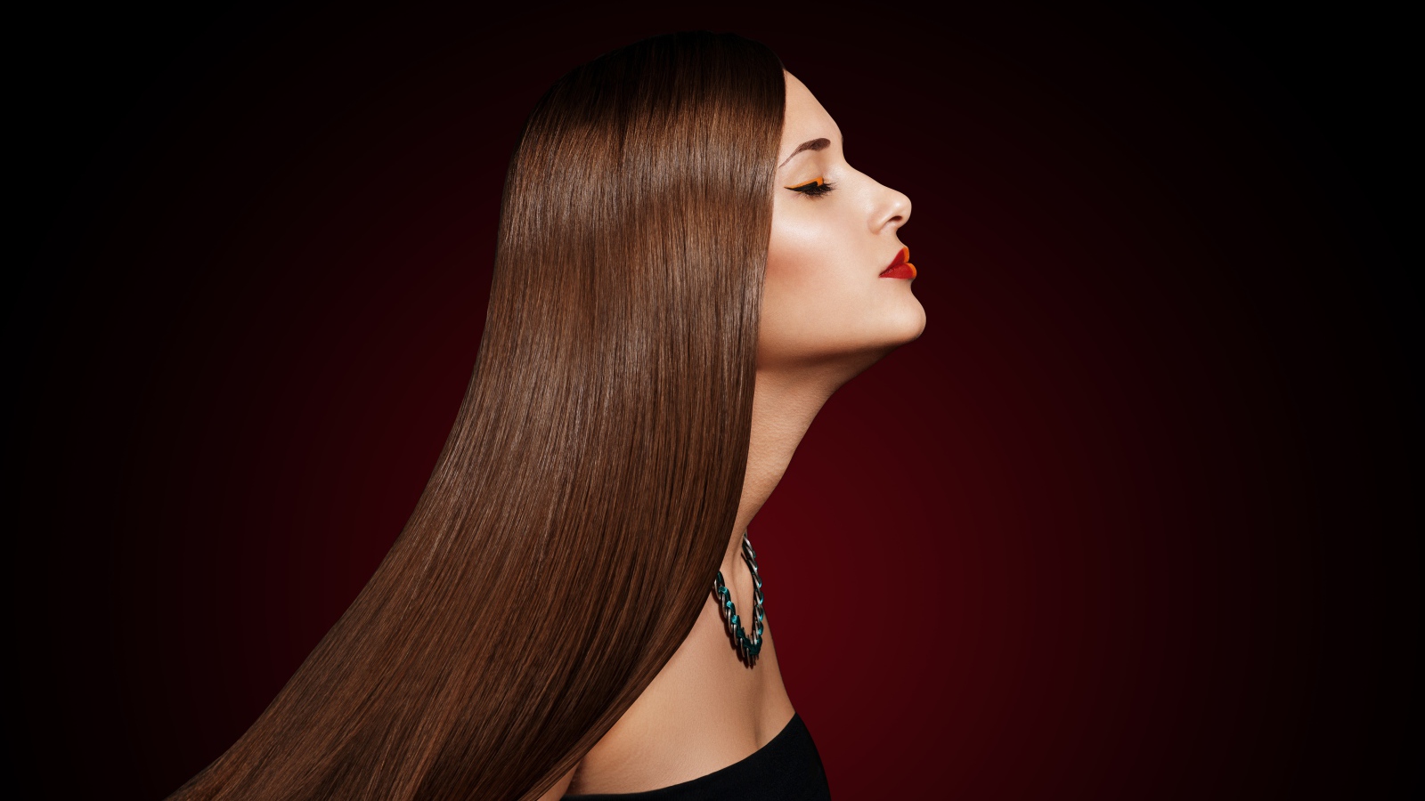 Длинноволосая шатенка с закрытыми глазами на красном фоне