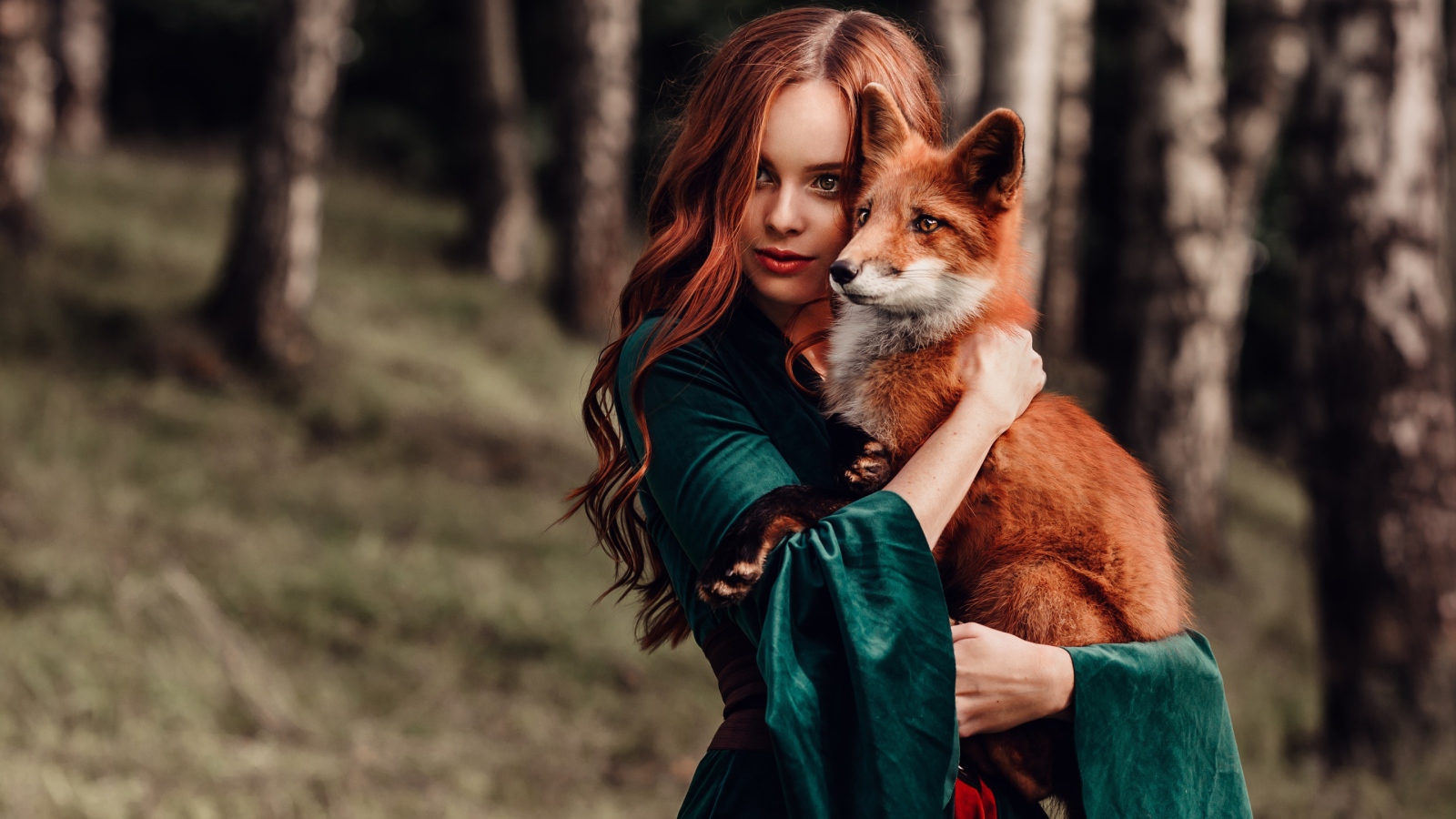 Рыжеволосая девушка в зеленом платье с лисой в руках 