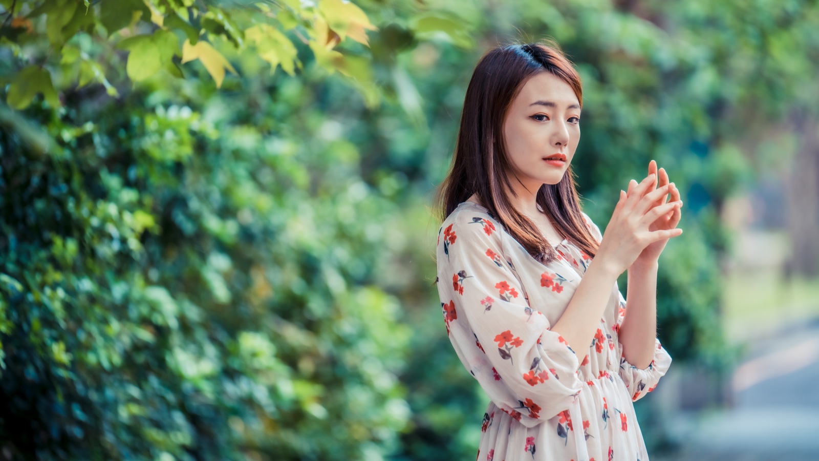 Грустная девушка азиатка в платье в парке