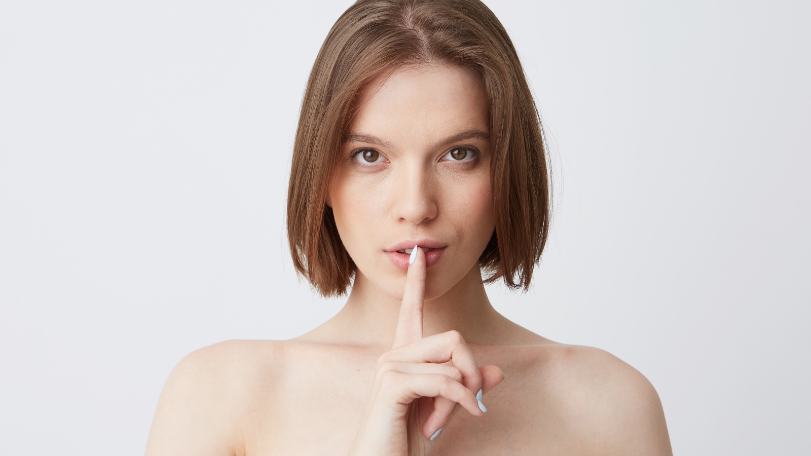 Девушка с короткой стрижкой с пальцем у рта 