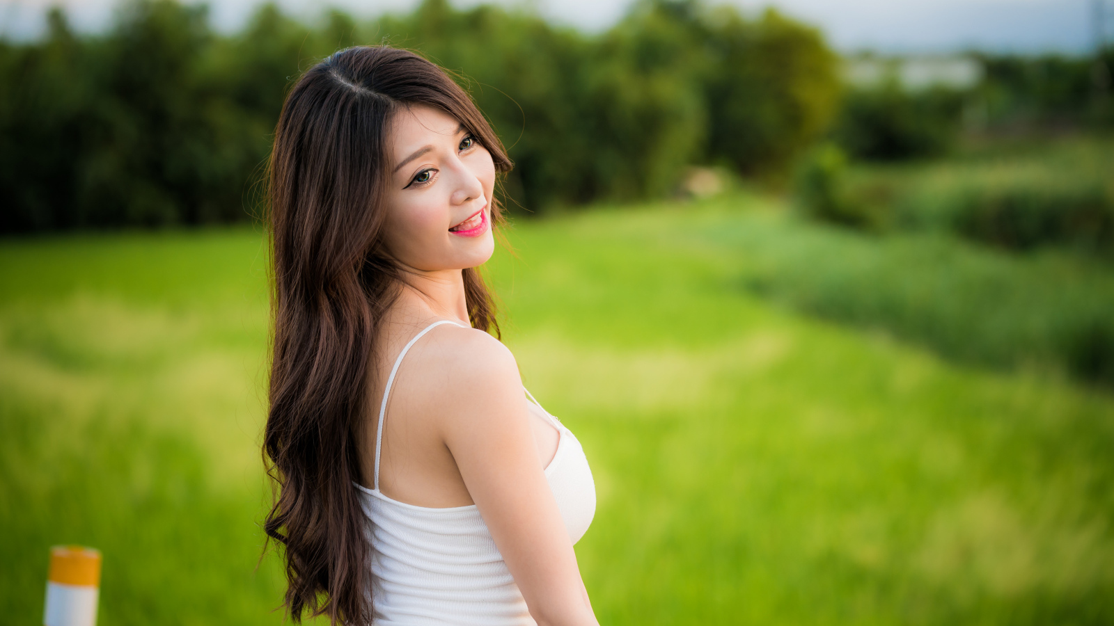 Улыбающаяся девушка азиатка на фоне зеленой травы