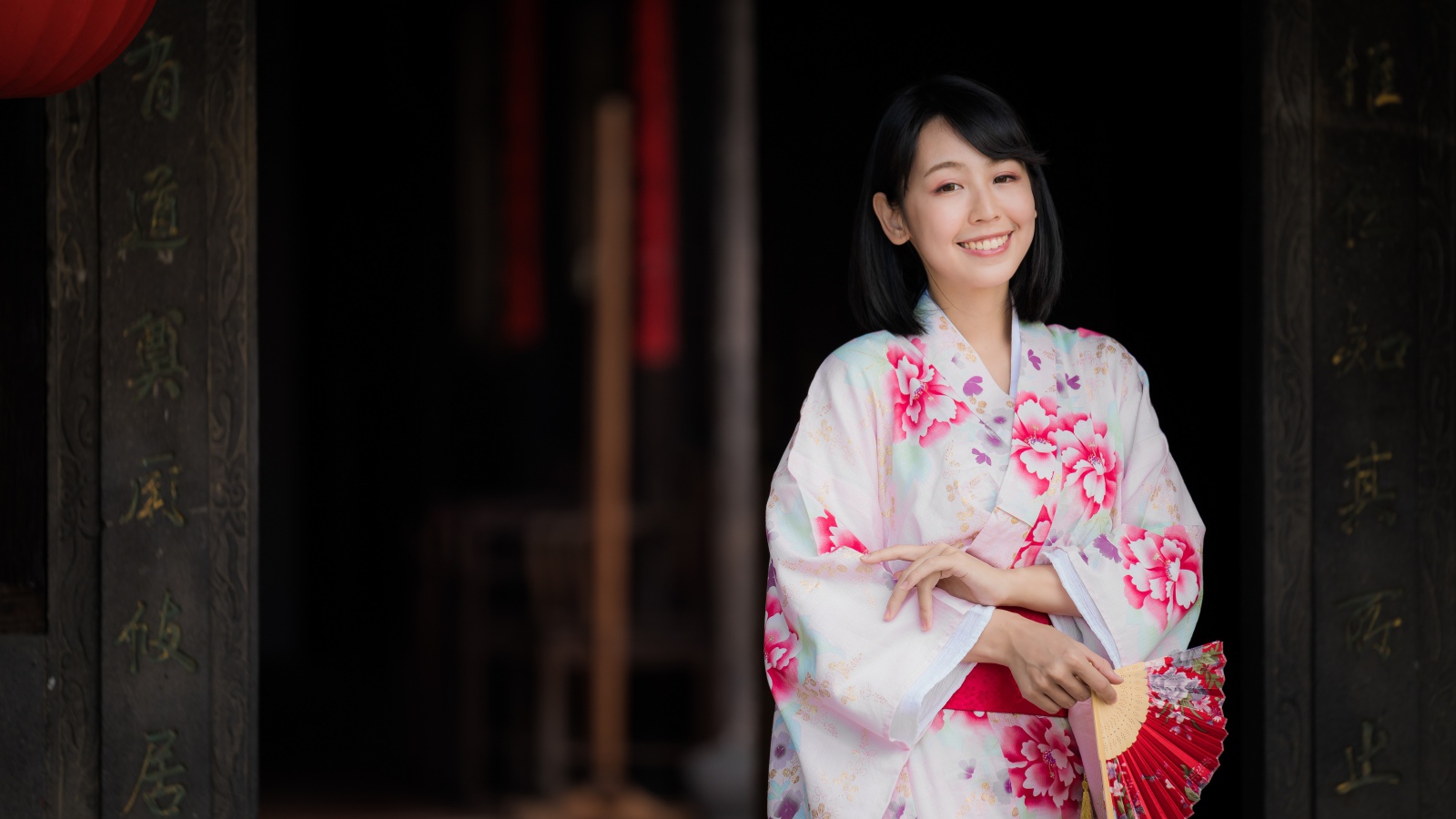 Улыбающаяся девушка азиатка в кимоно с веером в руке
