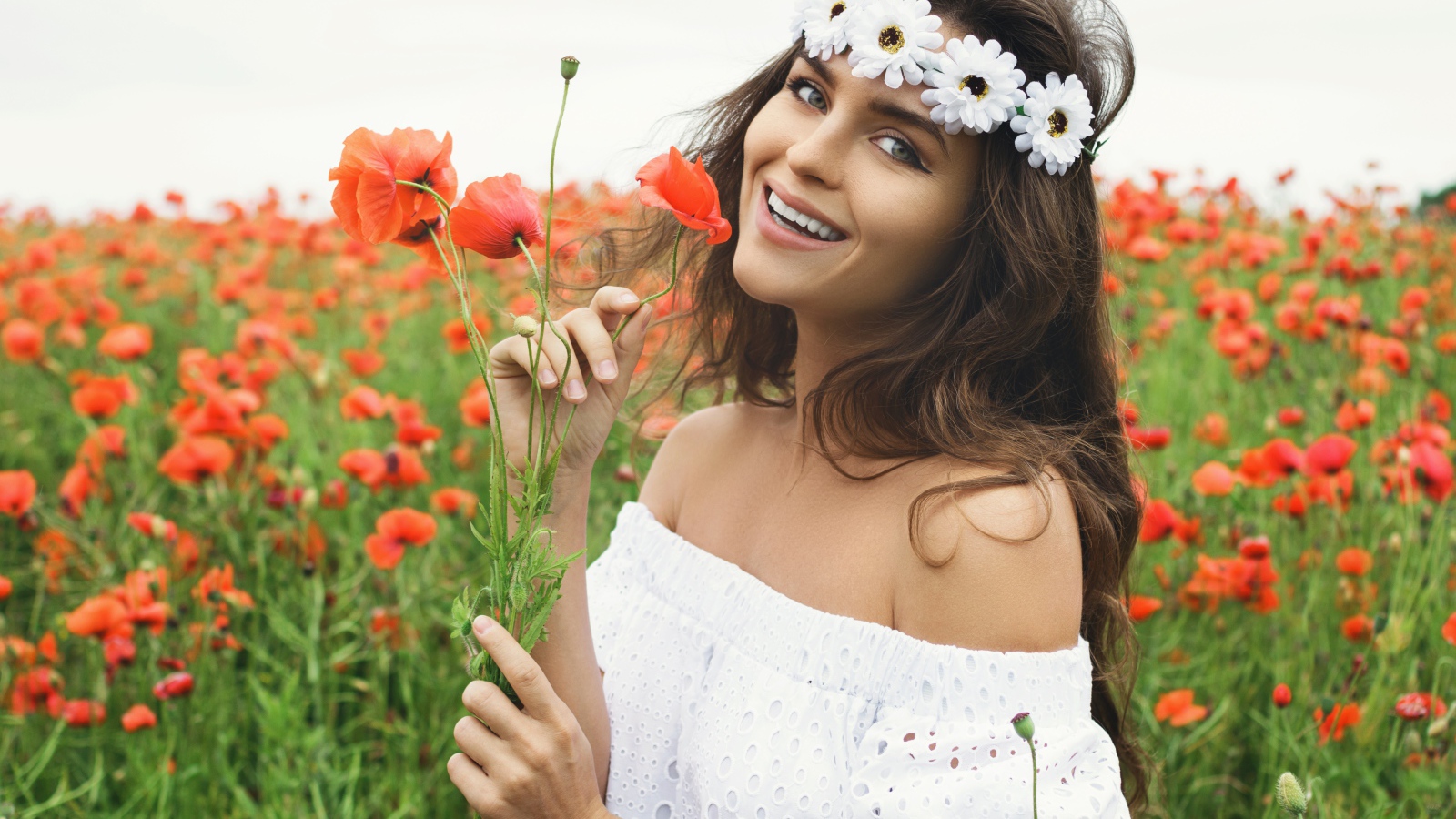 Улыбающаяся девушка в белом платье на поле с маками