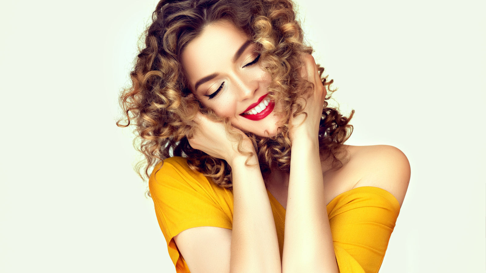 Улыбающаяся девушка с закрытыми глазами на белом фоне