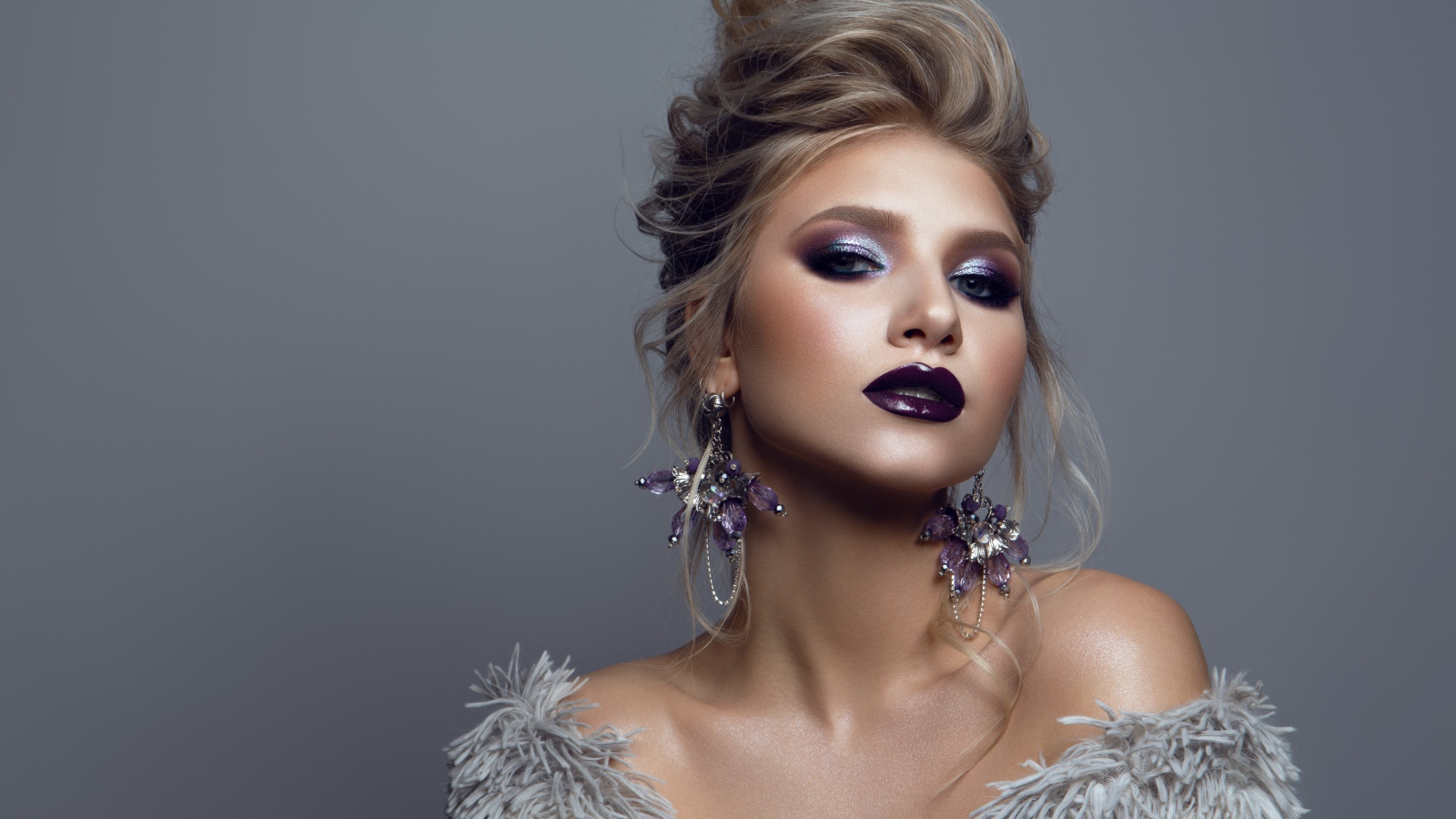 Эффектная девушка с ярким макияжем на сером фоне