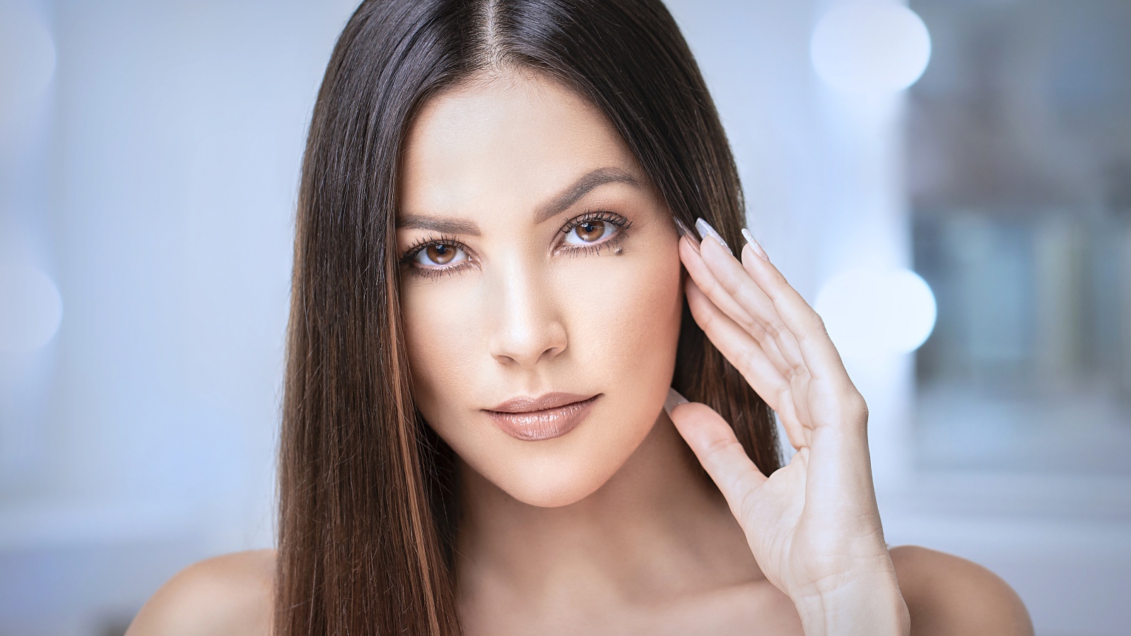 Стильная кареглазая длинноволосая брюнетка с рукой у лица