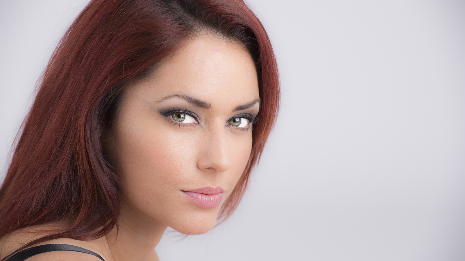 Лицо стильной девушки с зелеными глазами на сером фоне