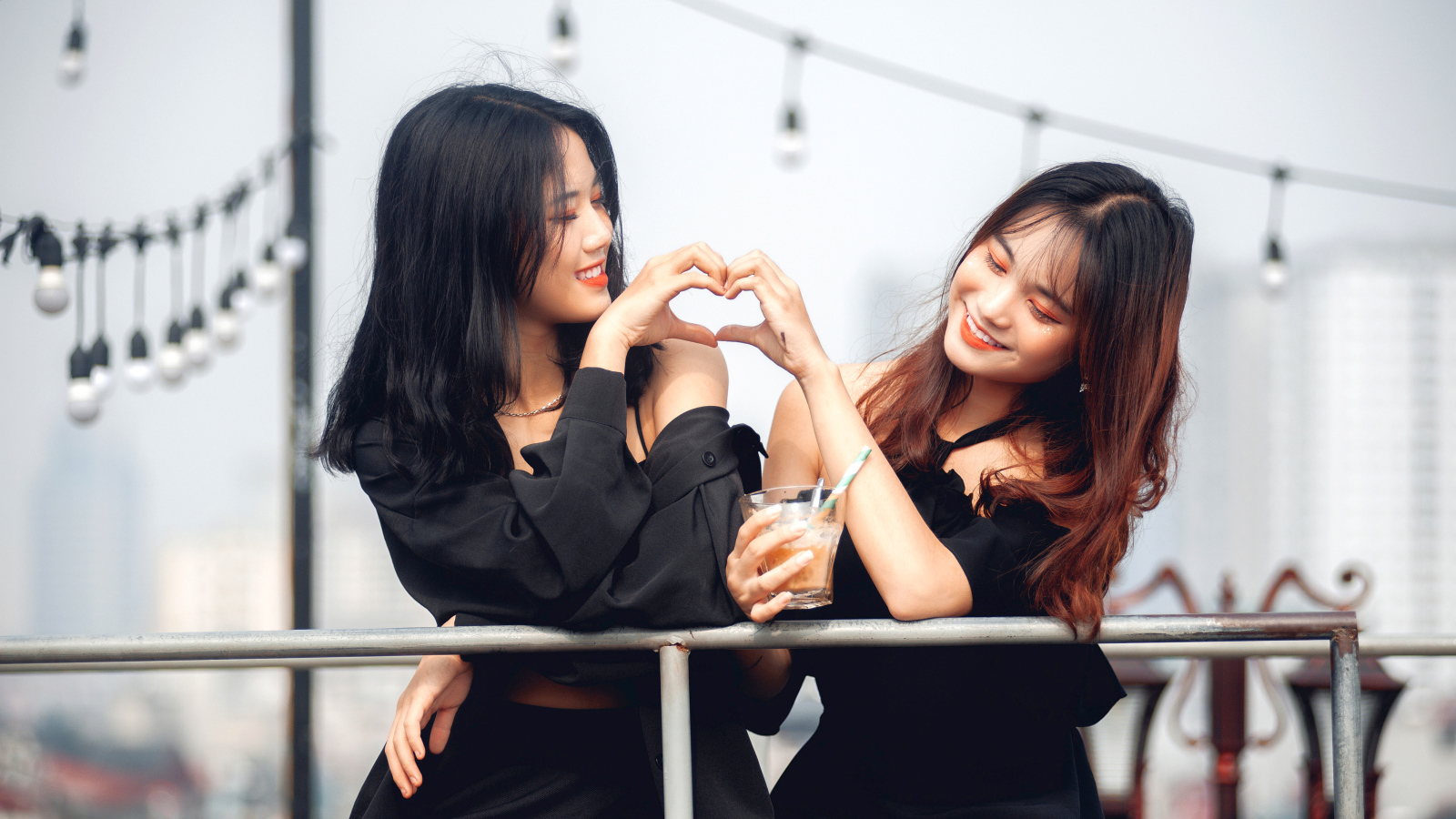 Две девушки азиатки делают сердце руками 