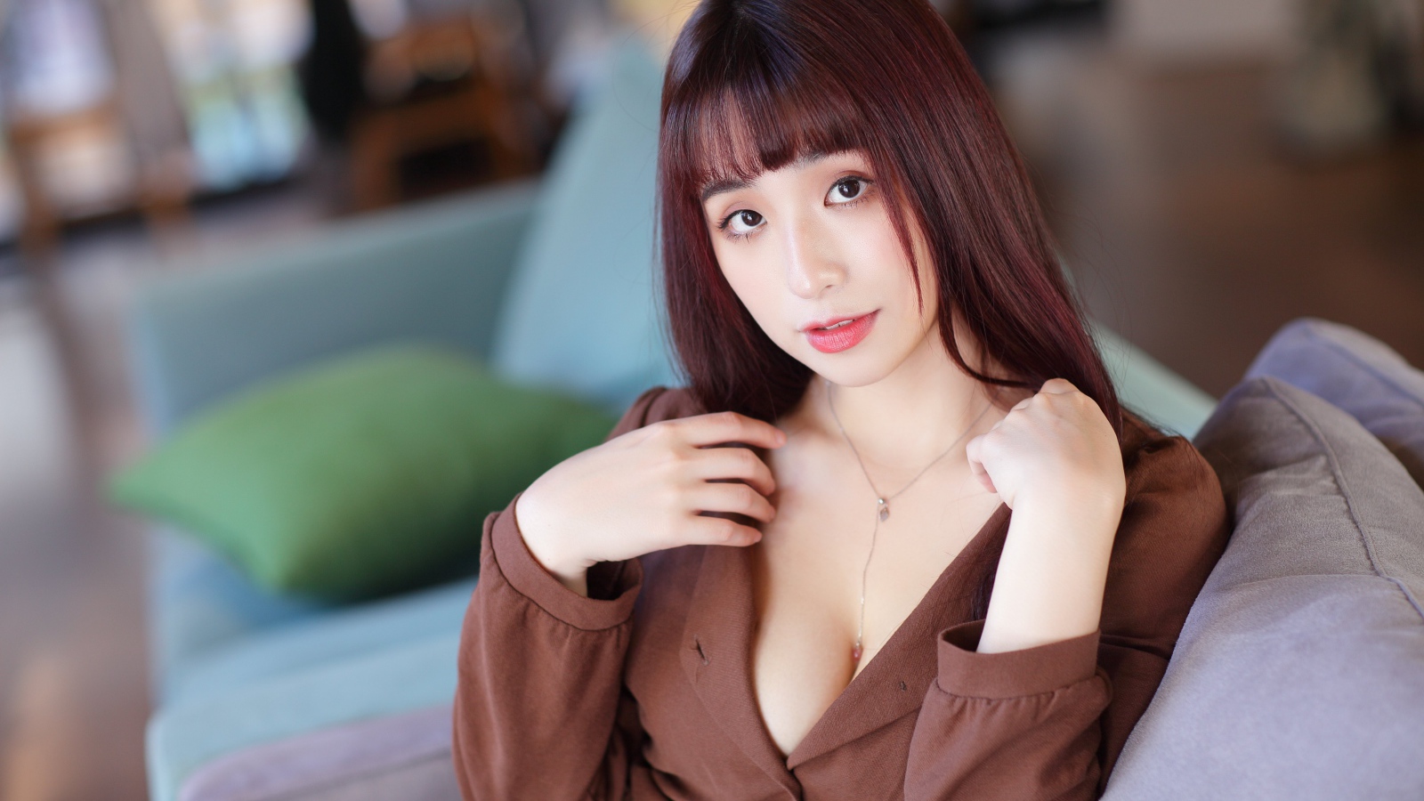 Молодая азиатка сидит на диване 