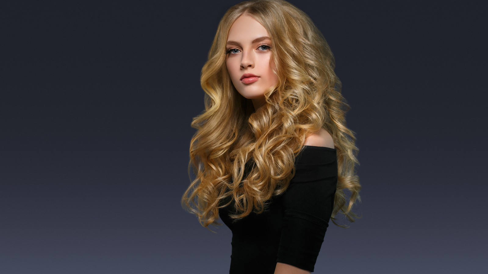 Молодая блондинка с красивыми длинными волосами в черном платье