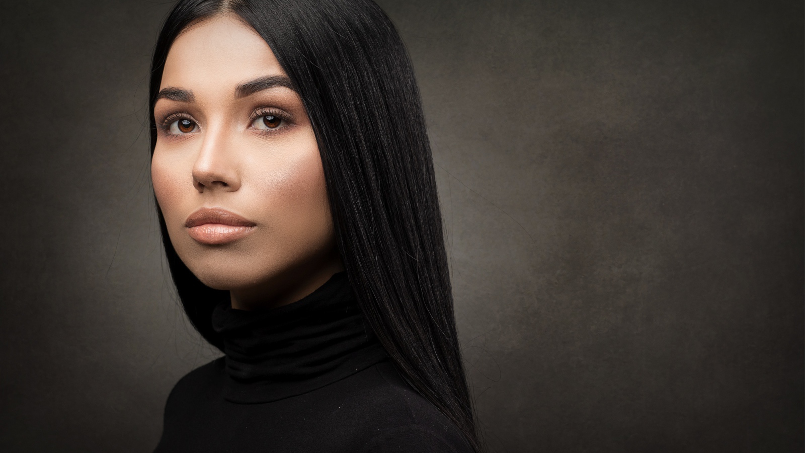 Молодая длинноволосая шатенка на сером фоне