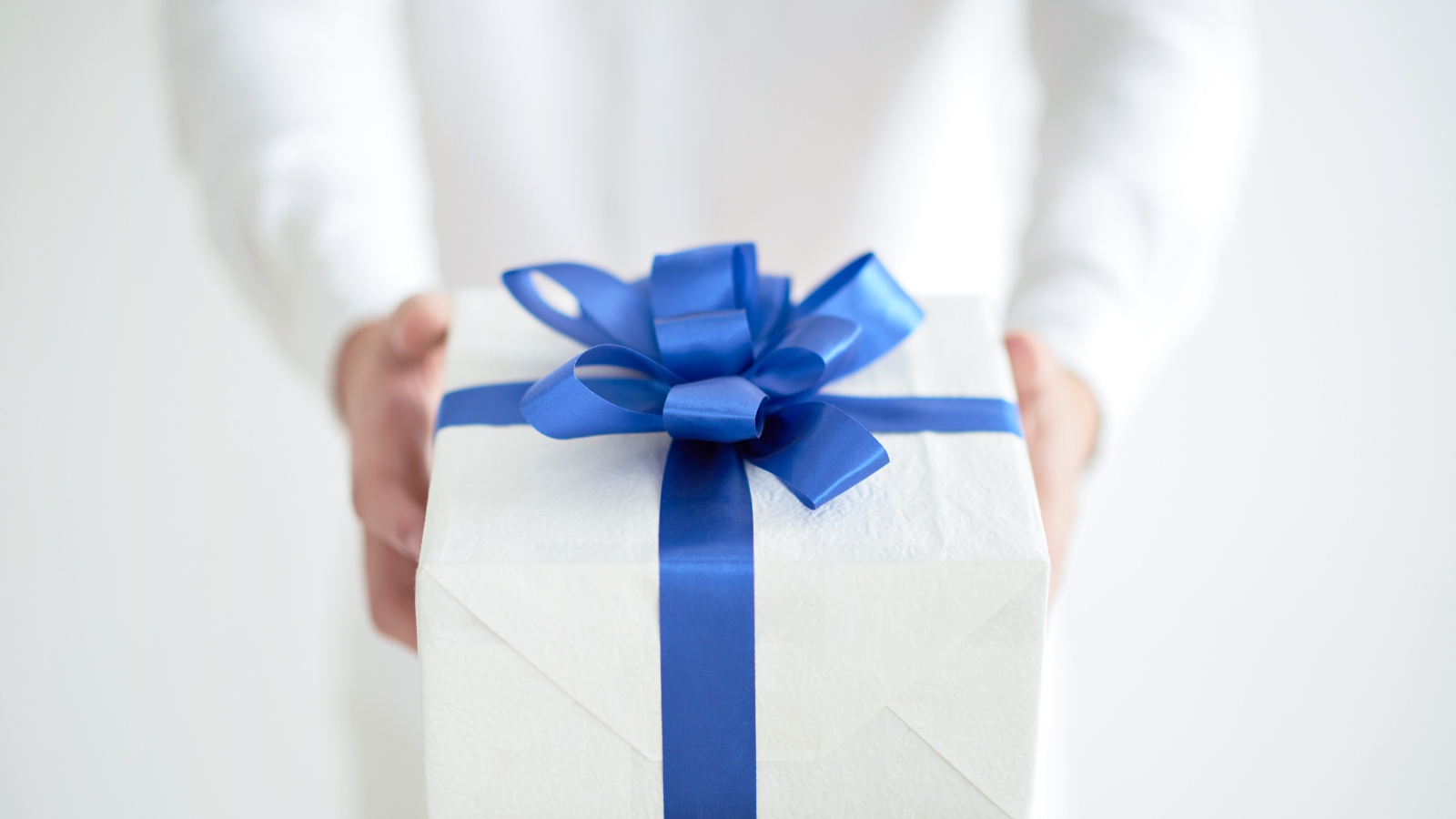 Gift with a blue bow in hands