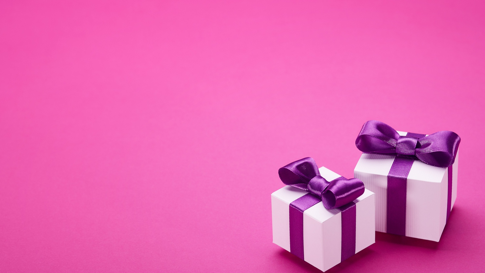 Два подарка с бантами на розовом фоне 