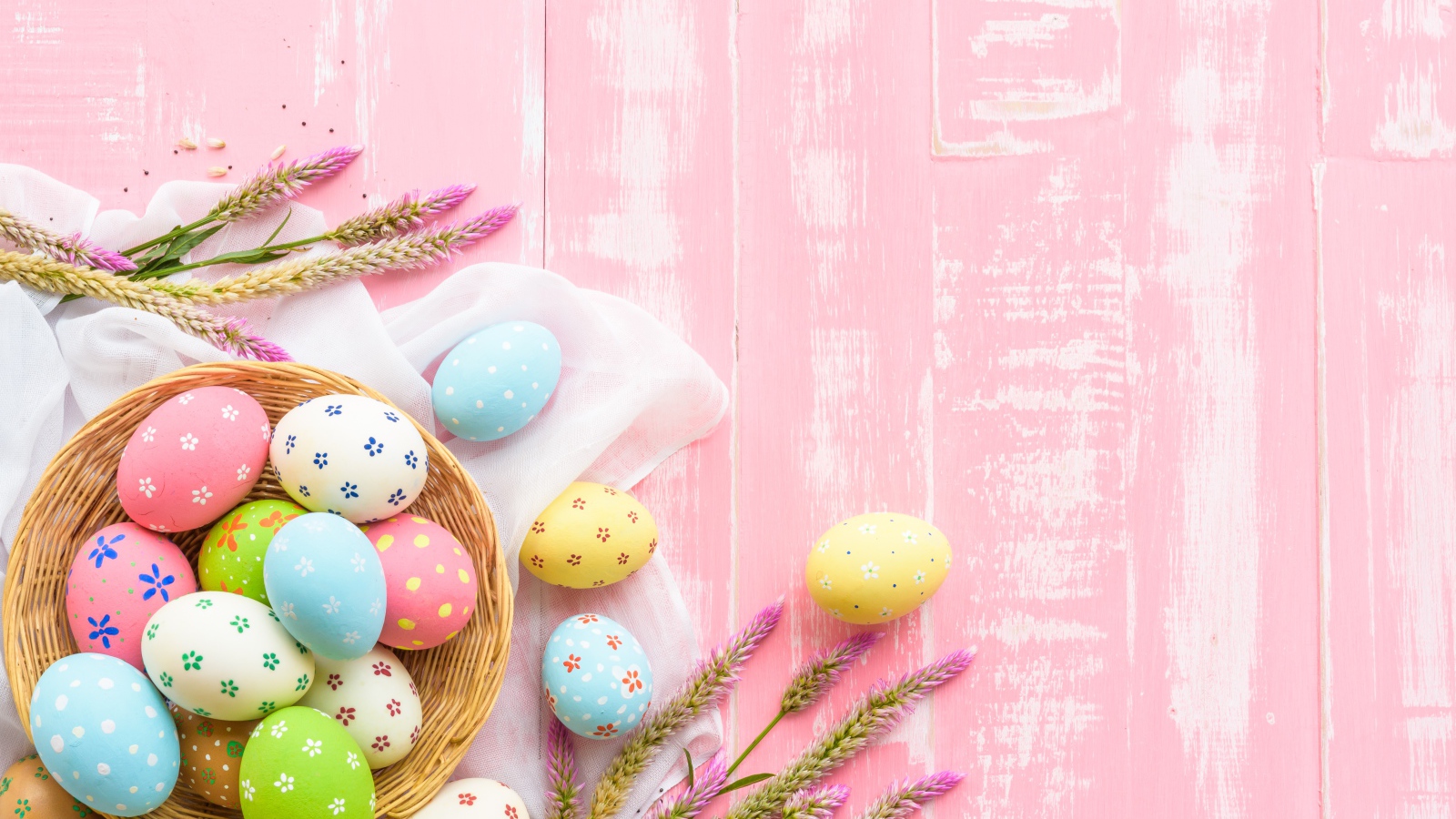Корзина с крашеными яйцами на розовом фоне