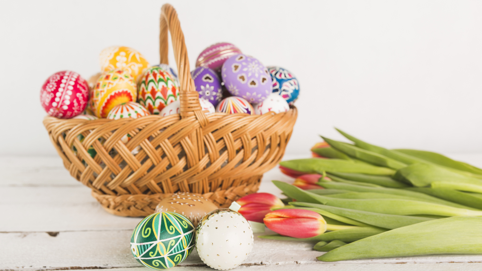 Basket with multi-colored eggs and tulips for Easter Light holiday