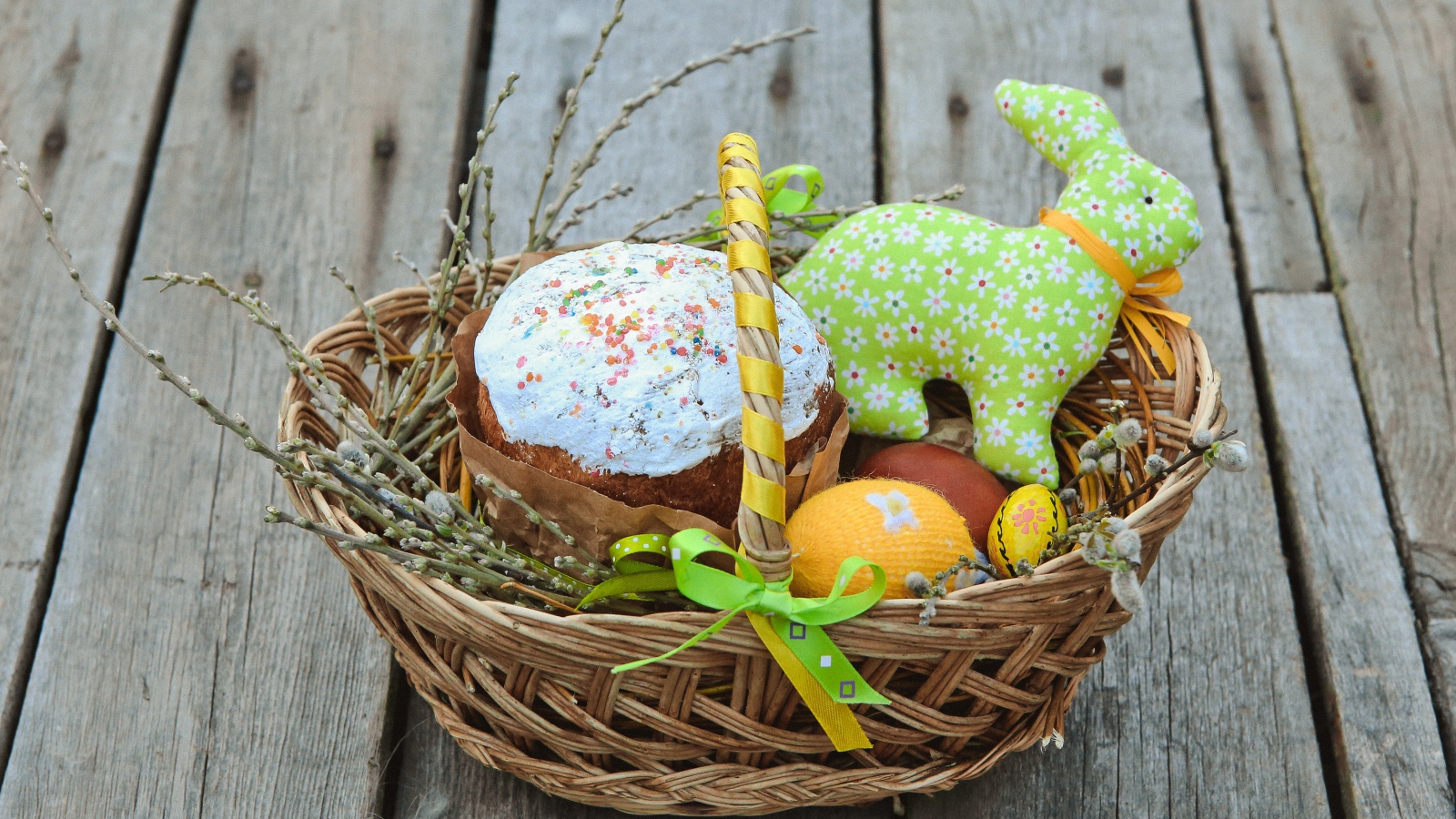Пасхальный кулич в корзинке с игрушками  на столе 