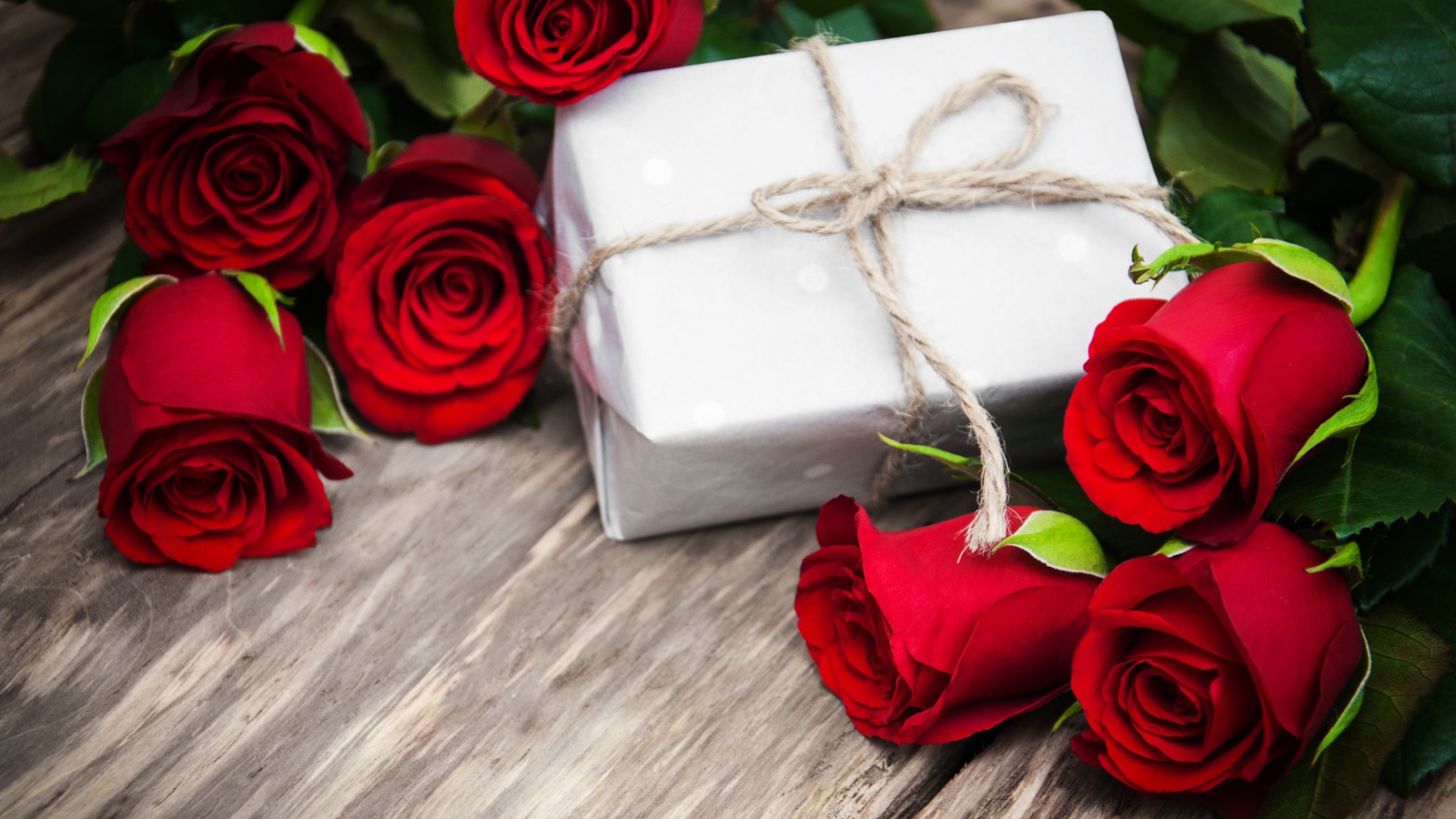Букет красных роз на столе с подарком на 8 марта