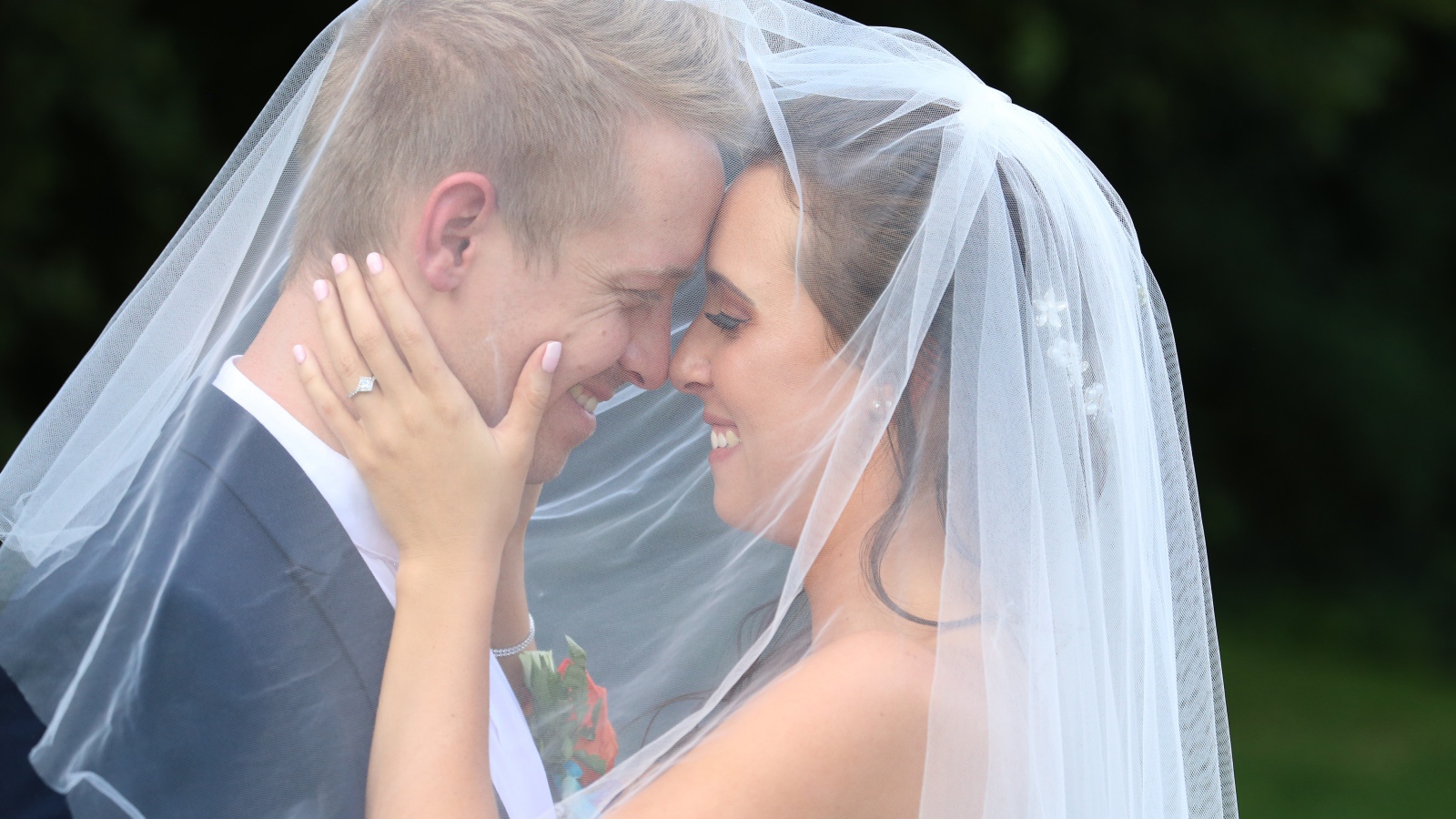 Жених и невеста стоят под белой фатой