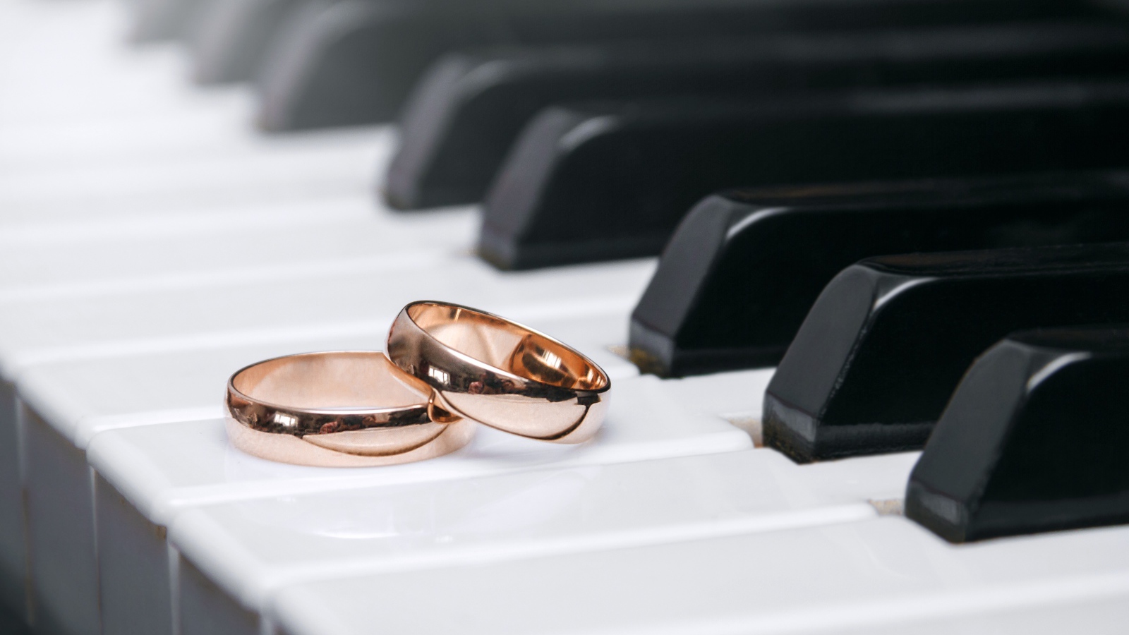 Два золотых обручальных кольца на клавишах рояля 