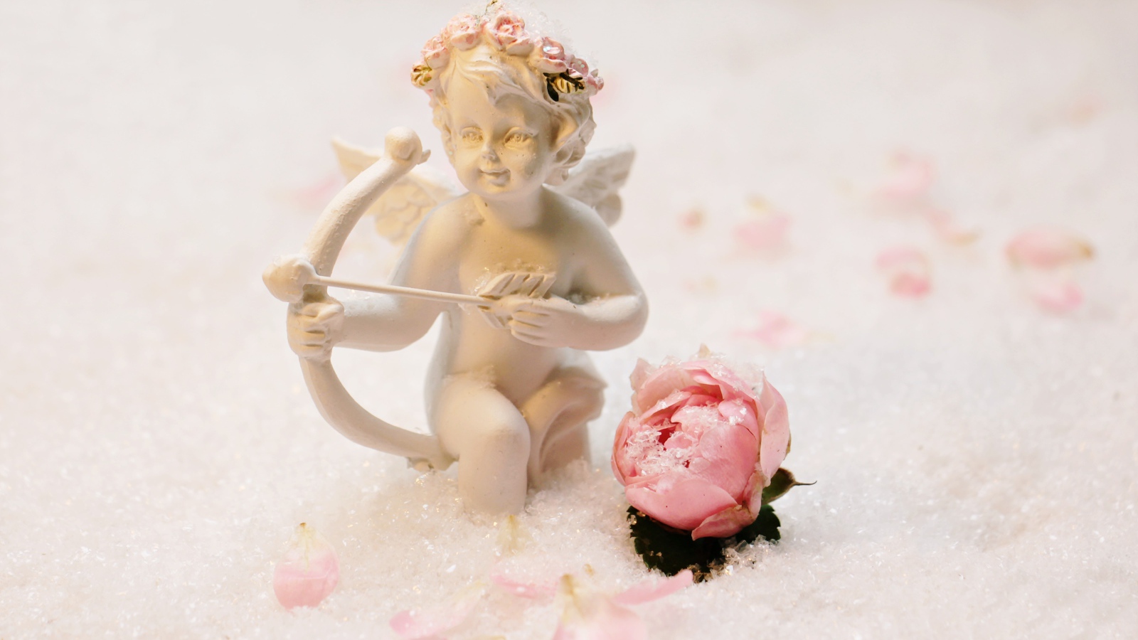 Статуэтка купидона с розой на снегу