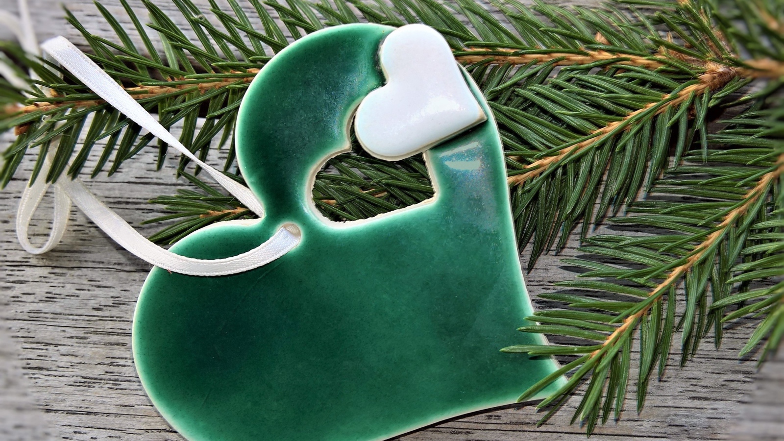 Зеленое сердце с еловой веткой на столе 