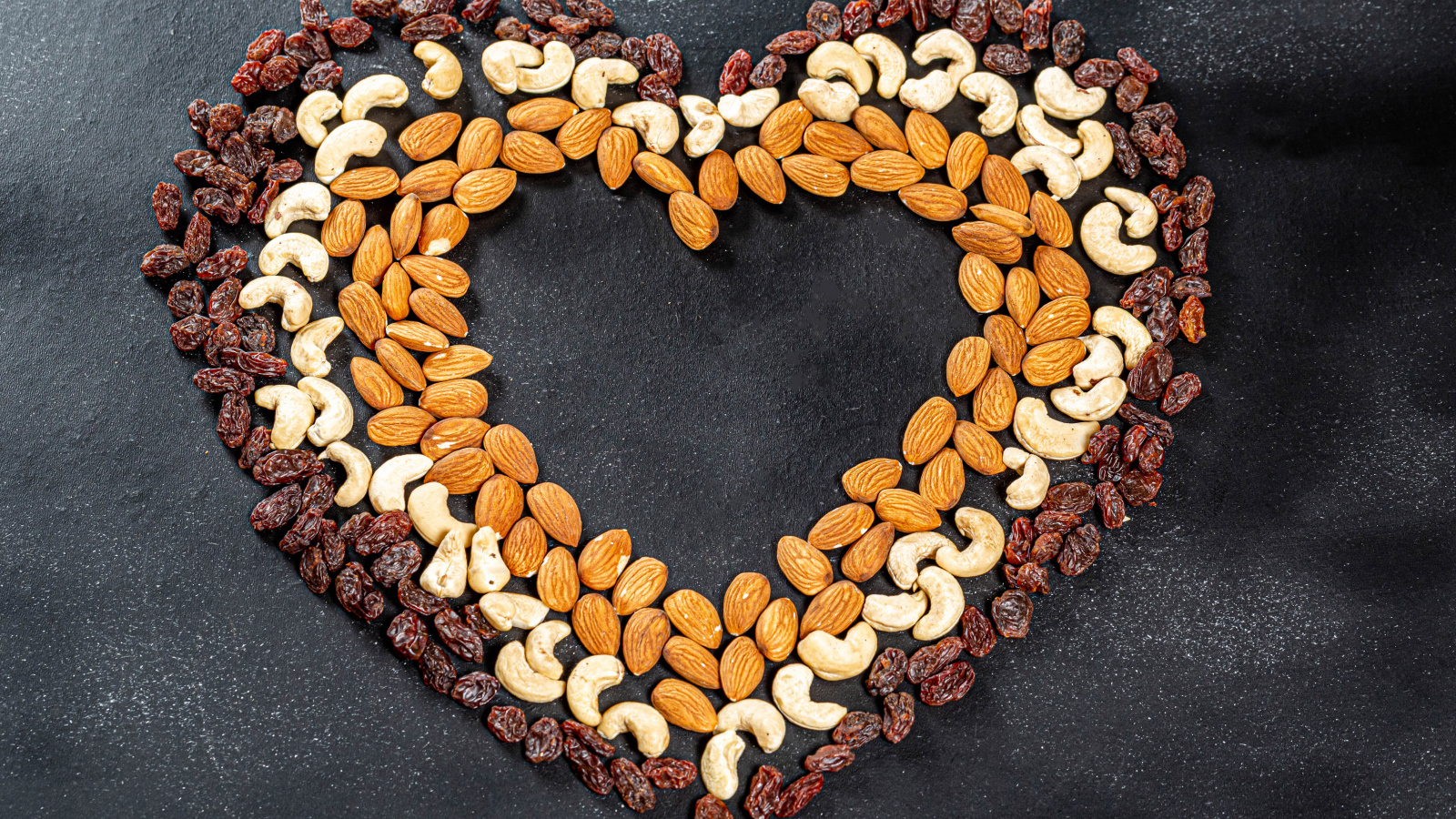 Сердце из орехов и изюма на сером фоне