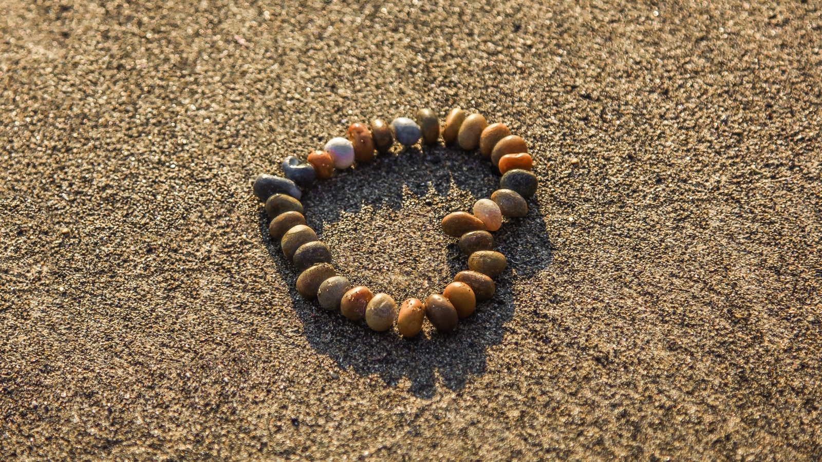 Сердце из мелкий морских камей на песке 