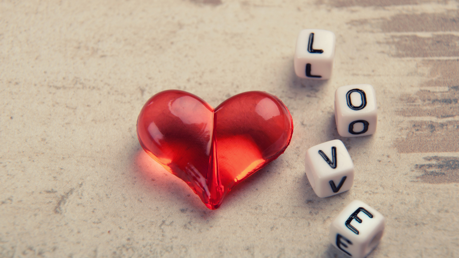 Красное стеклянное сердце на столе с кубиками