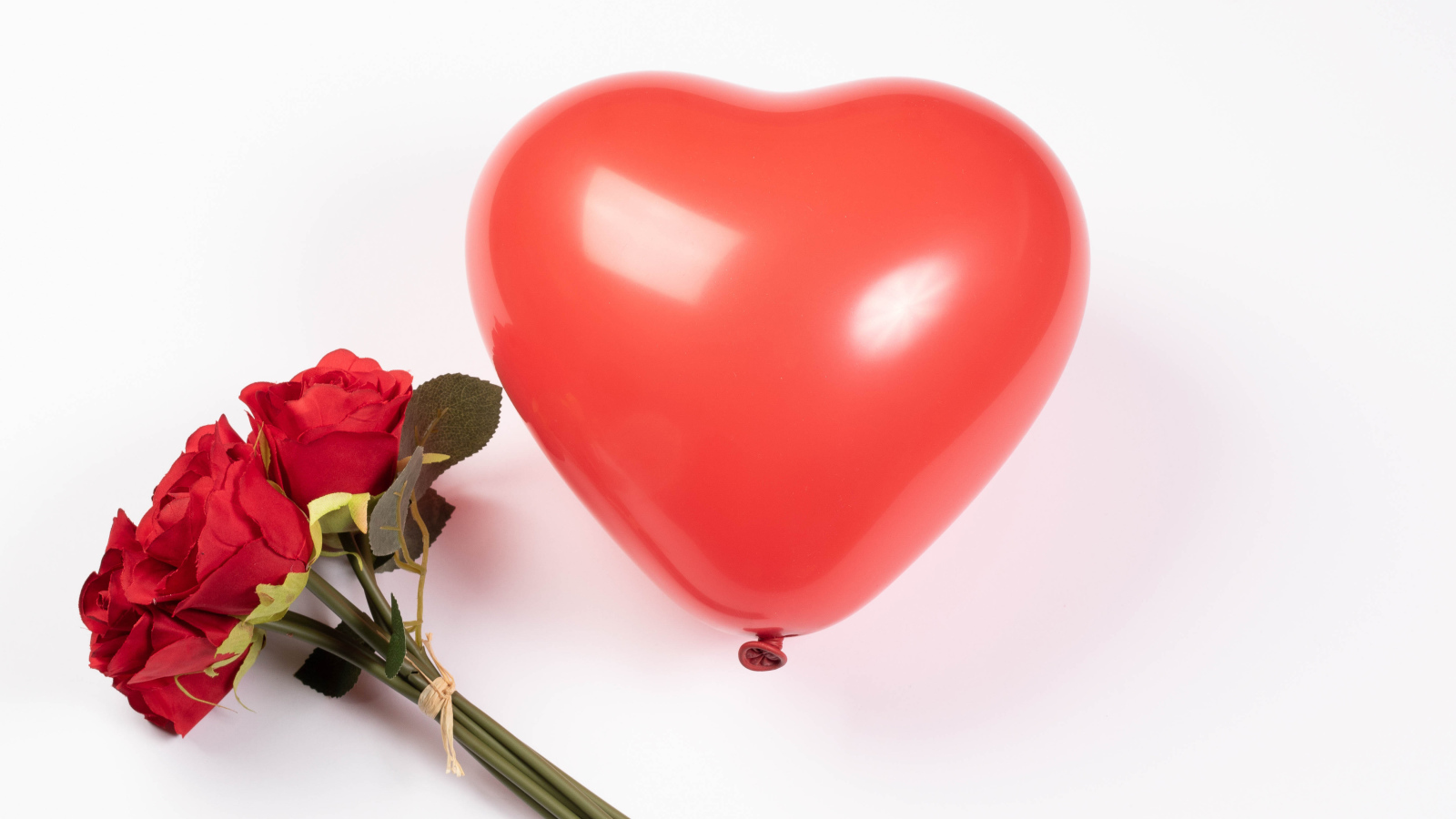 Красный шарик в форме сердца с букетом роз на белом фоне