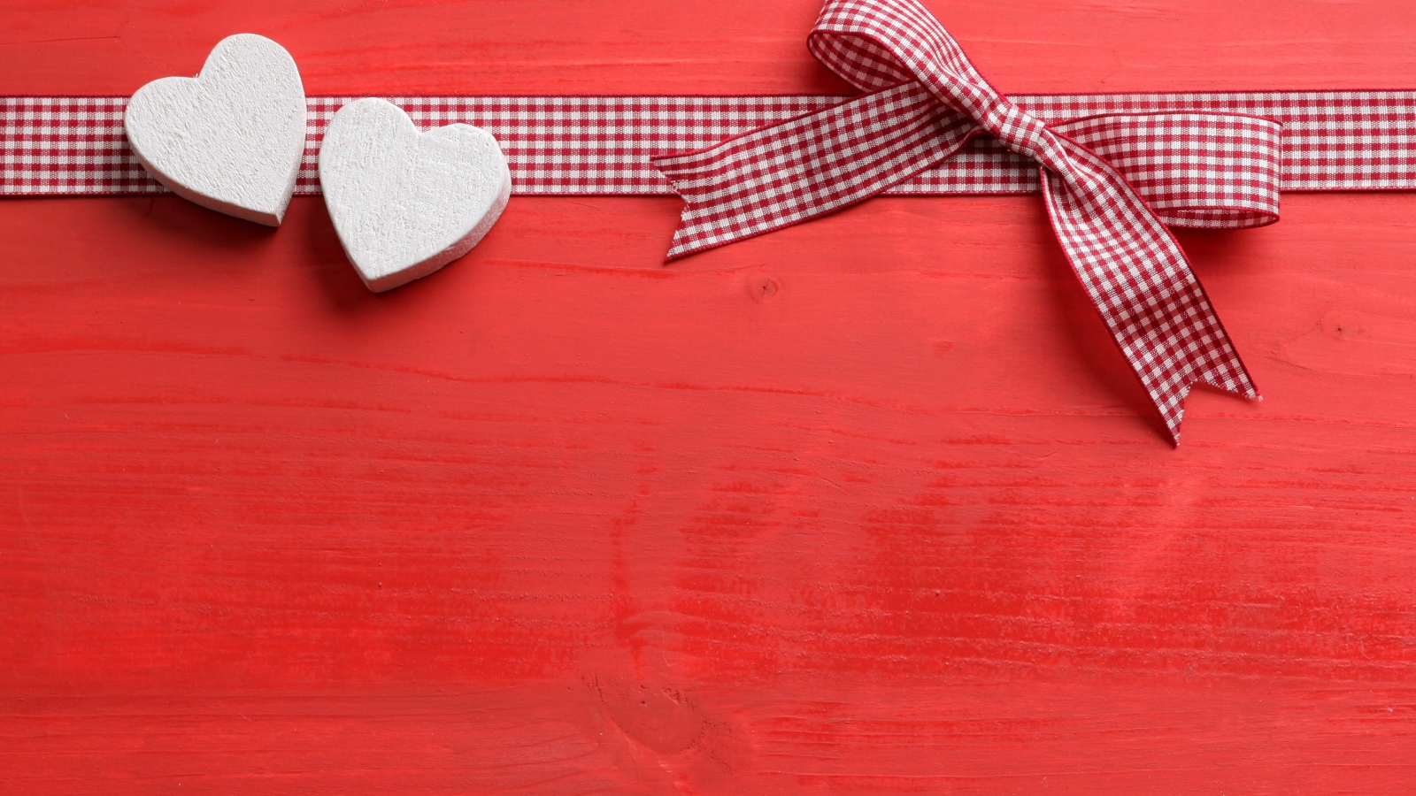Two hearts with a bow on a red background
