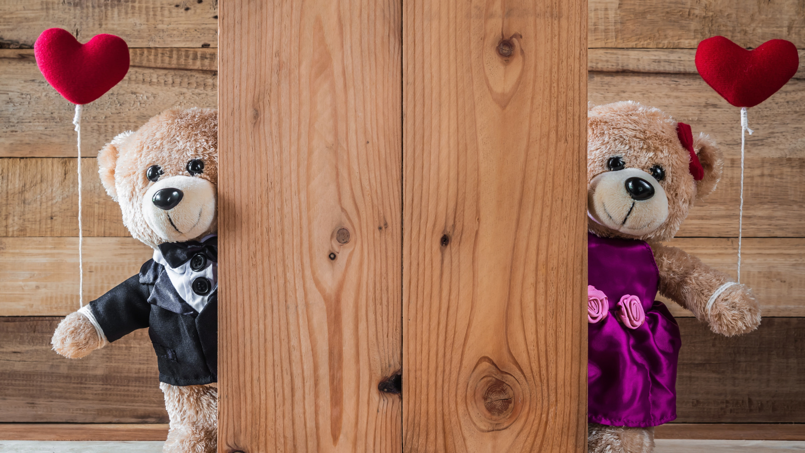 Два плюшевых медведя с сердечками у стены